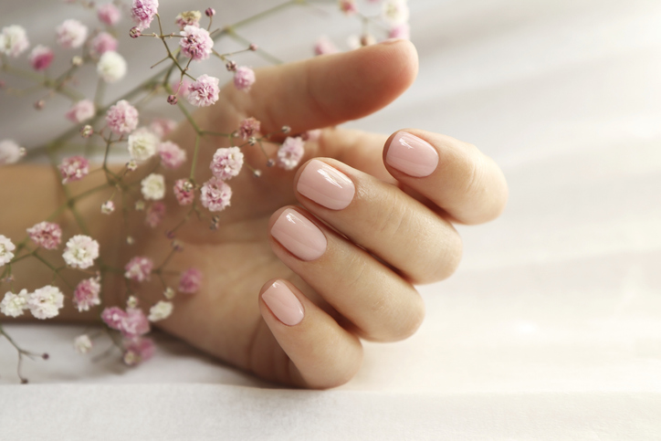 Light pink manicure on short nails .