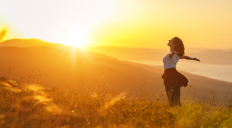 Happy woman on sunset in nature iwith open hands