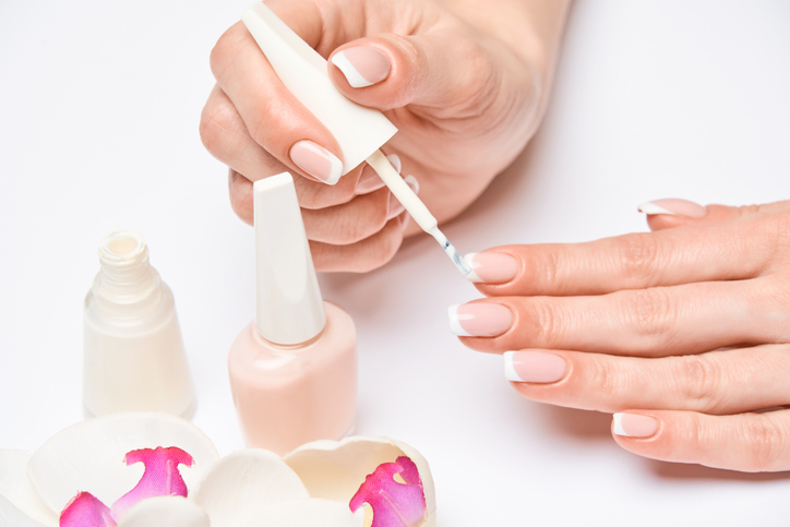 Beautiful Female Hands with French manicure over light grey background