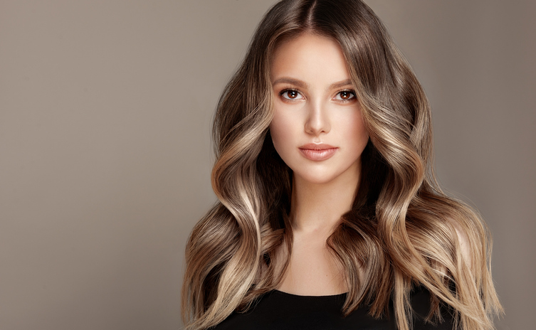 Young, brown haired beautiful model with wavy, dense, dyed long hair. Excellent hair waves.Hairdressing art and coloration of hair.