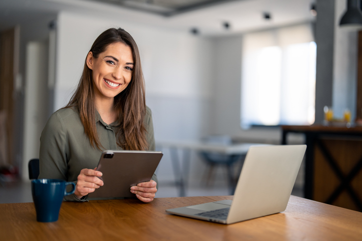 Portrait of smiling fulfilled young woman holding digital tablet device