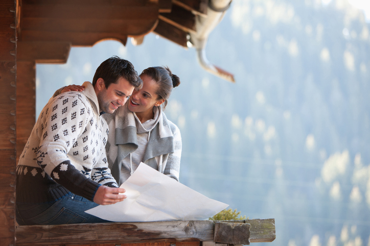 Smiling couple looking at map on cabin porch