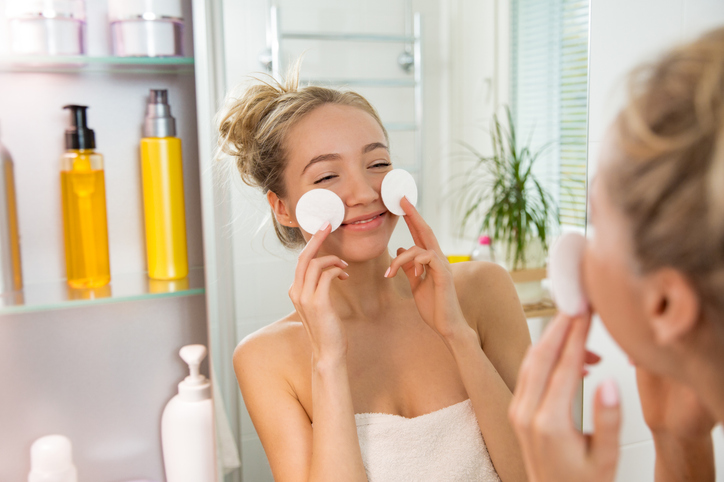 Young beautiful woman cleaning her face skin with cotton pad