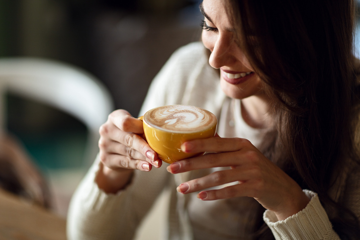 Happy woman enjoying in cup of fresh coffee
