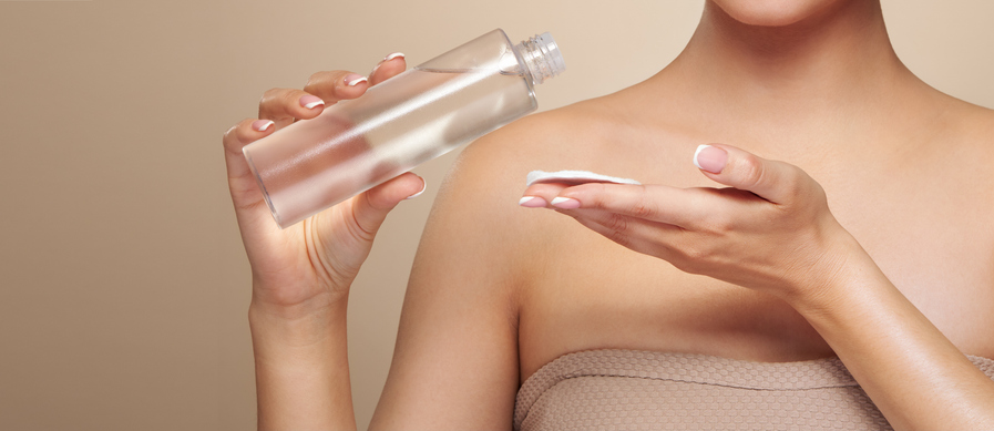 Smiling woman holds bottle with cosmetic tonic